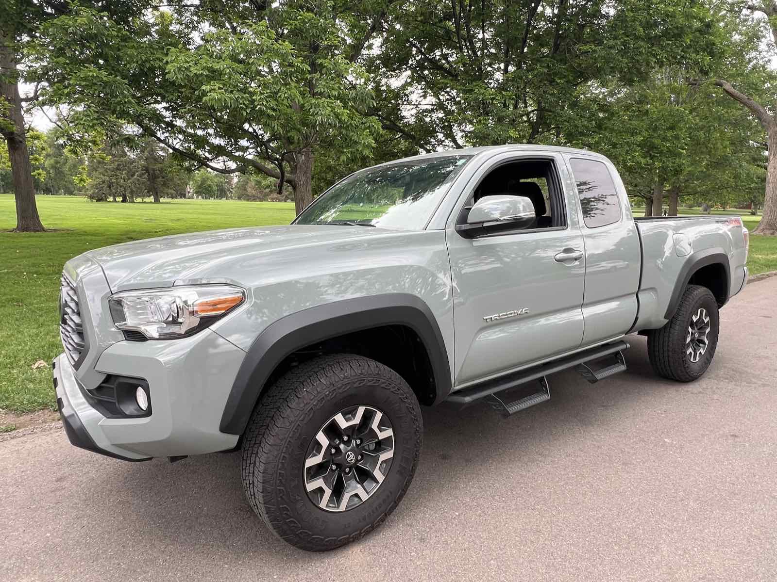 2023 Toyota Tacoma TRD Off-Road Access Cab in Lunar Rock, front three-quarter view, parked on grass under trees.