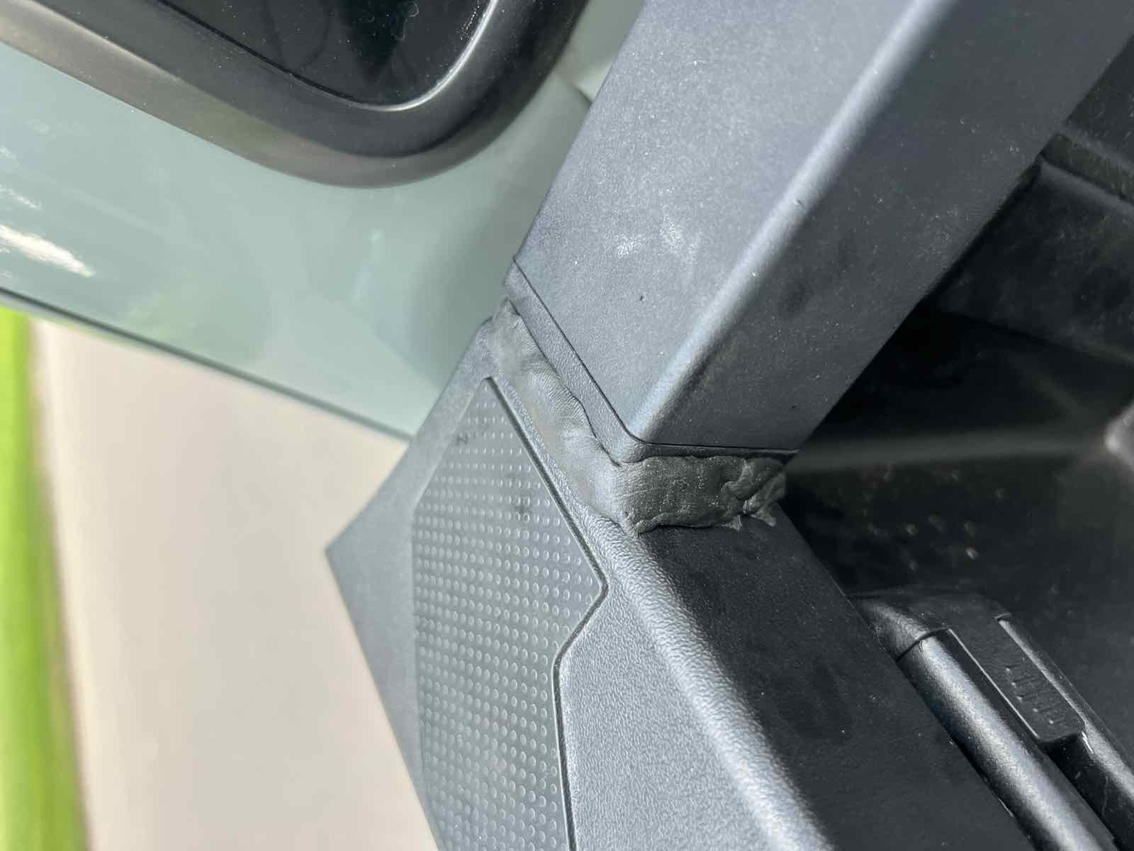 The same front corner near the cab on a 2023 Tacoma, now sealed with black butyl tape pressed into the gap between the front cap and the side rail.