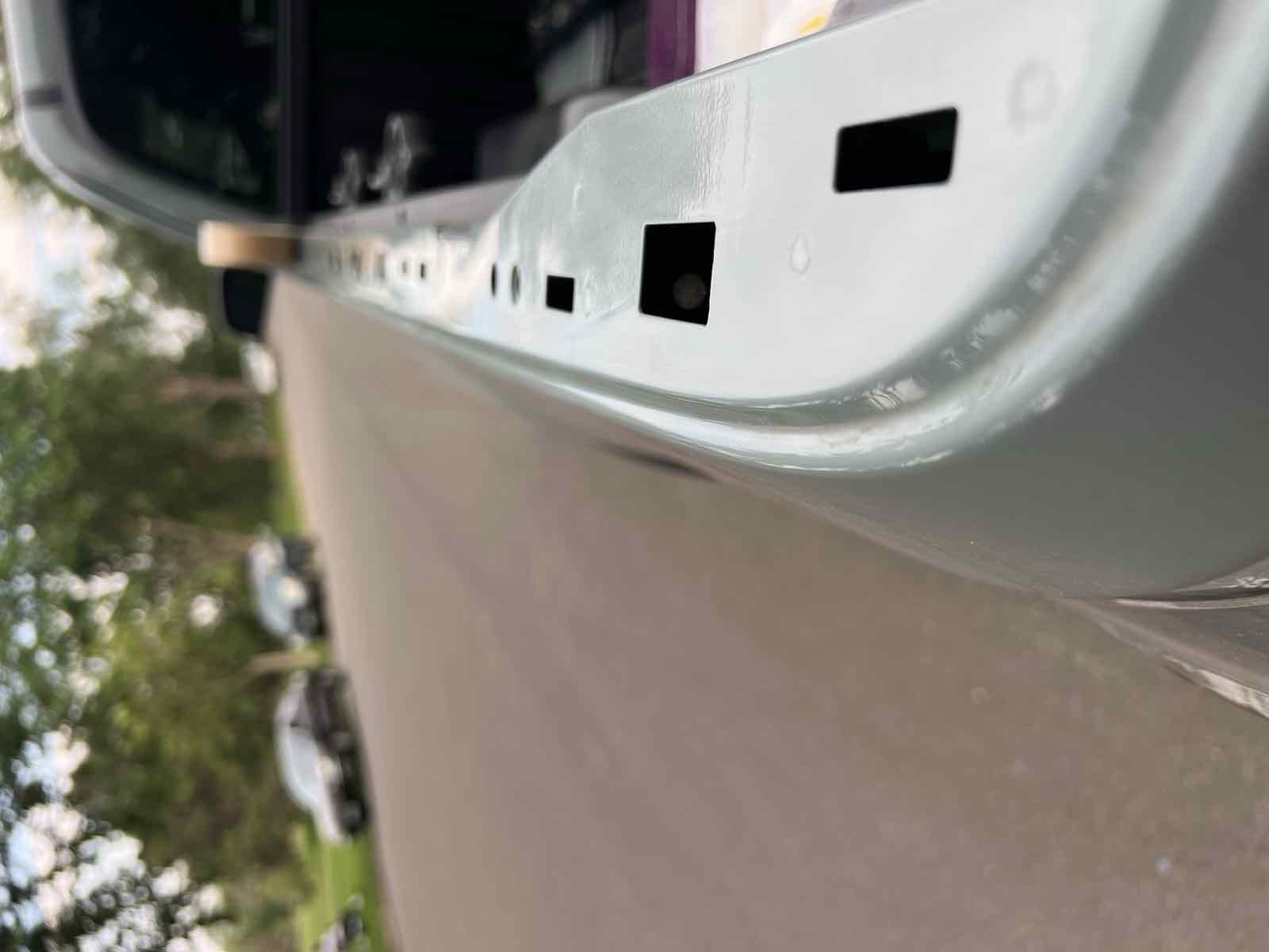 A 2023 Tacoma bed rail with the plastic cap removed, exposing a row of open rectangular holes along the top of the rail that let dust and water into the bed.