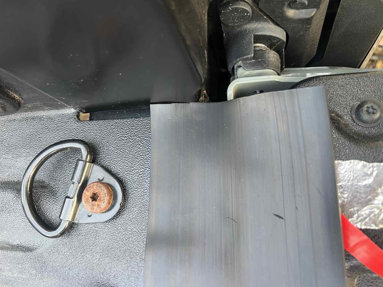 Close-up of the trimmed right-hand end of an installed ROK Block tailgate seal on a Tacoma, pressed flat against the bed floor.