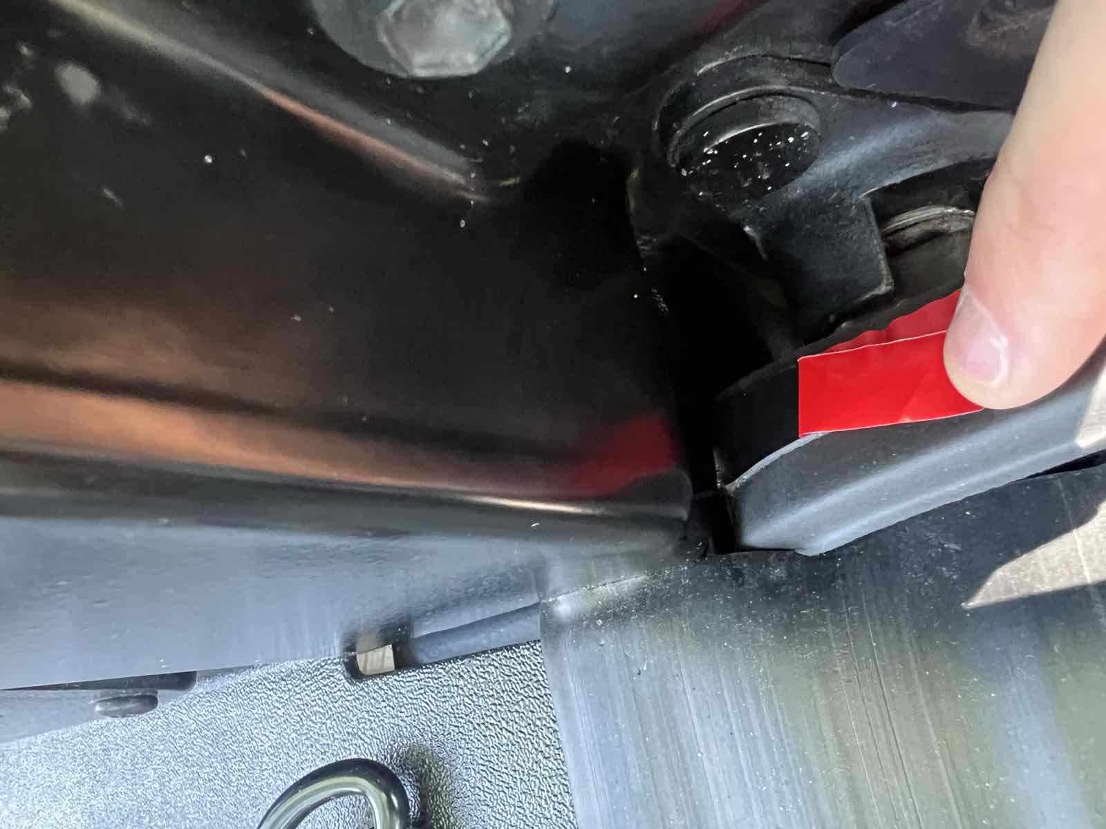 The first few inches of a black taper seal being pressed into place at the bottom of a Tacoma bedside, working upward.